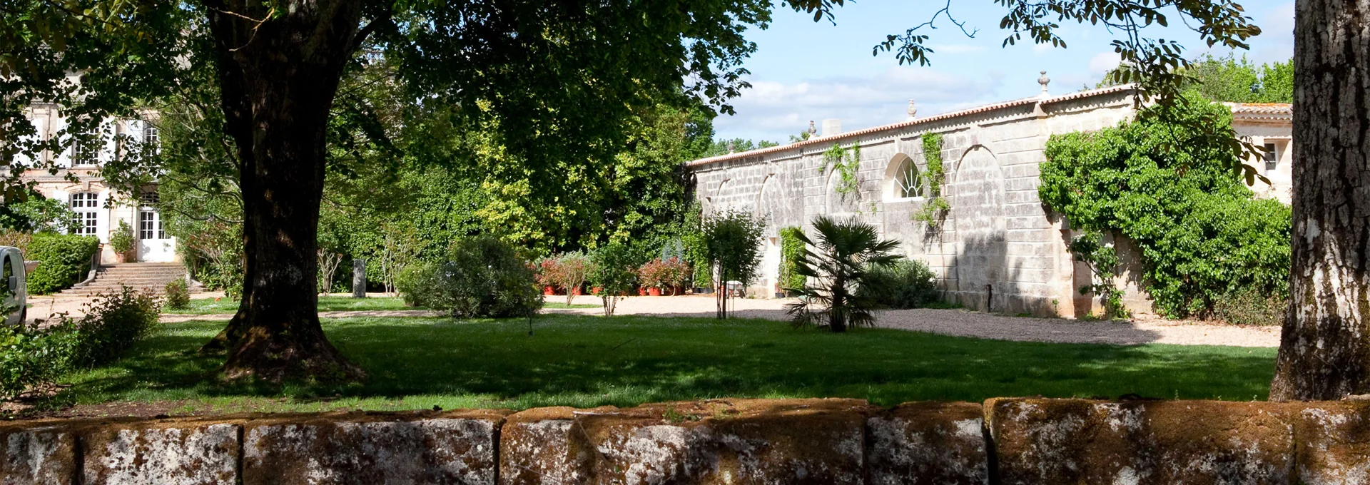 Les murs de pierre et les arbres du domaine, baignés de lumière